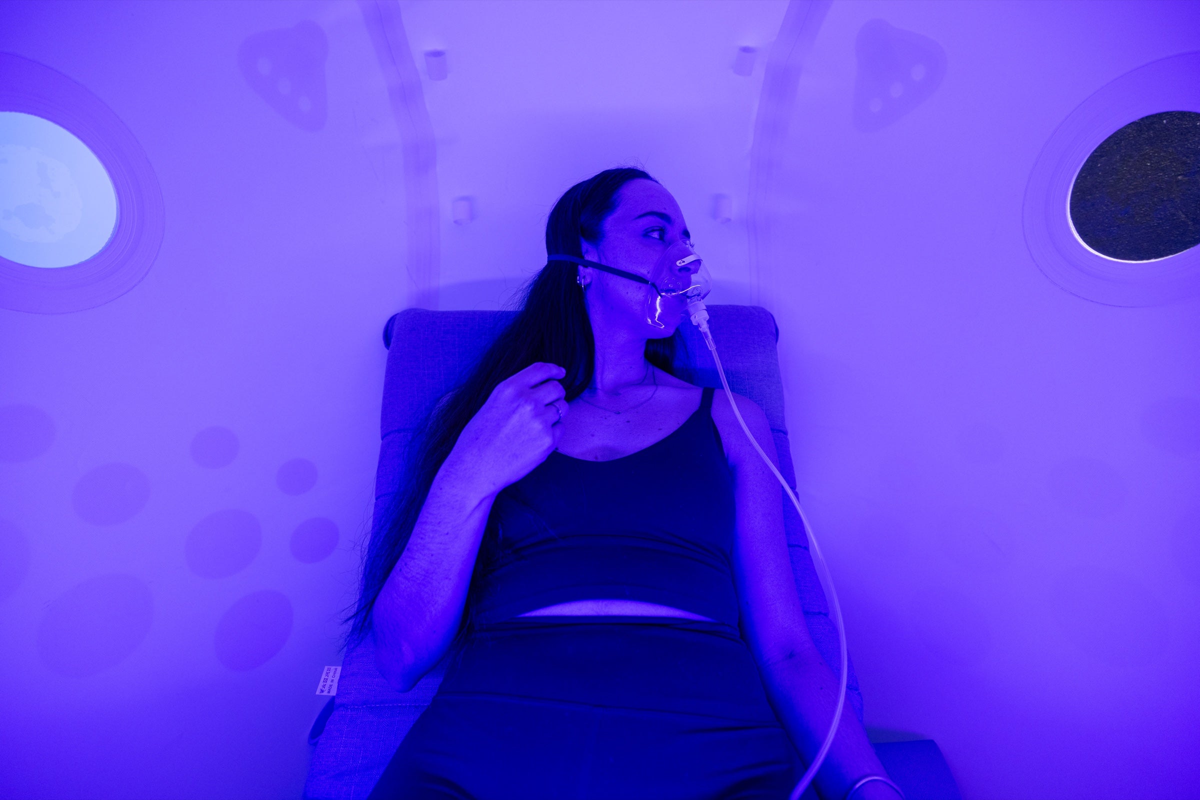 A woman wearing an oxygen mask during a session inside an Oxydise chamber