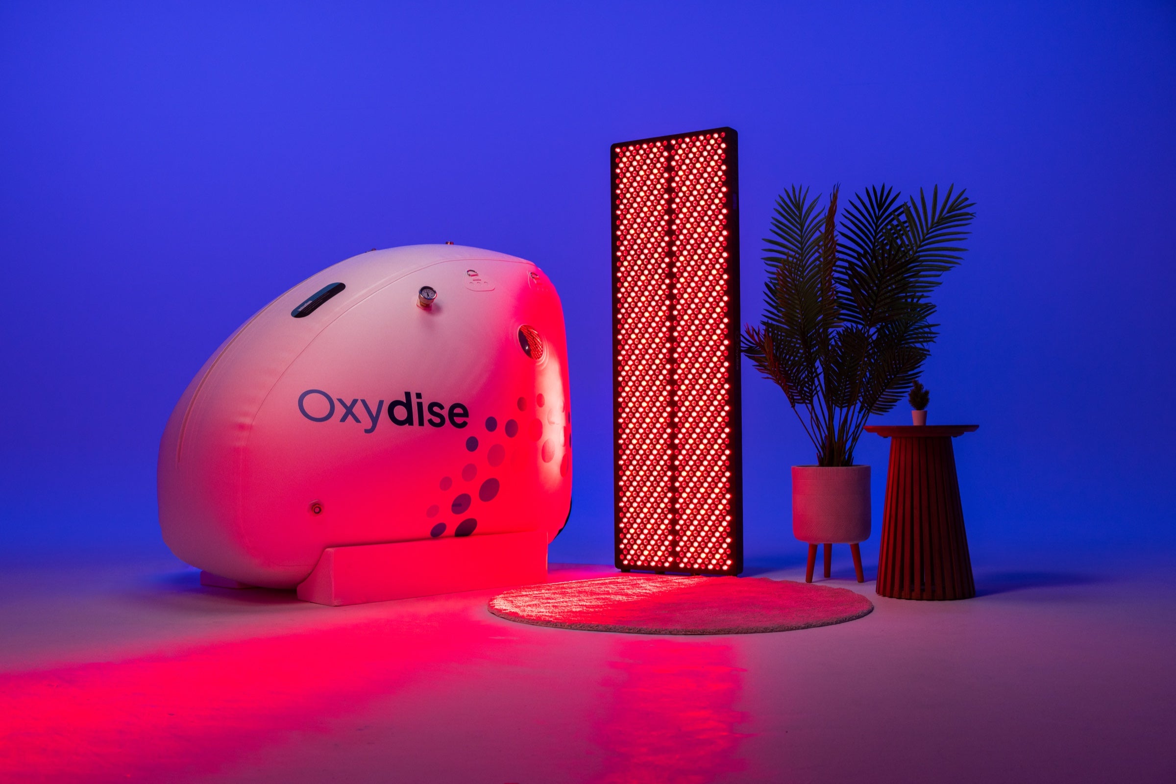 Oxydise chamber displayed with a Red Light Therapy panel in a styled studio setting