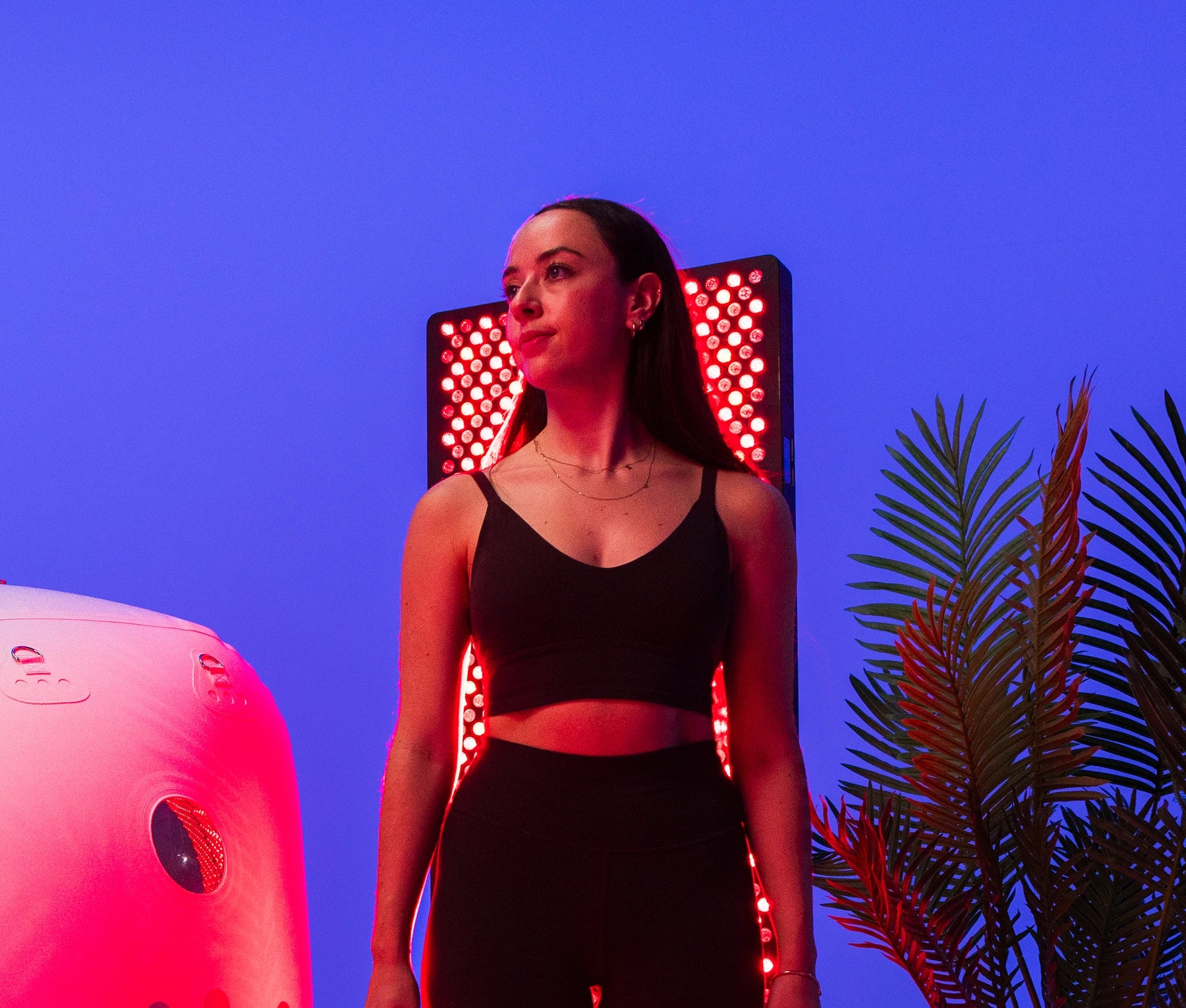 Woman standing in front of an illuminated Red Light Therapy panel