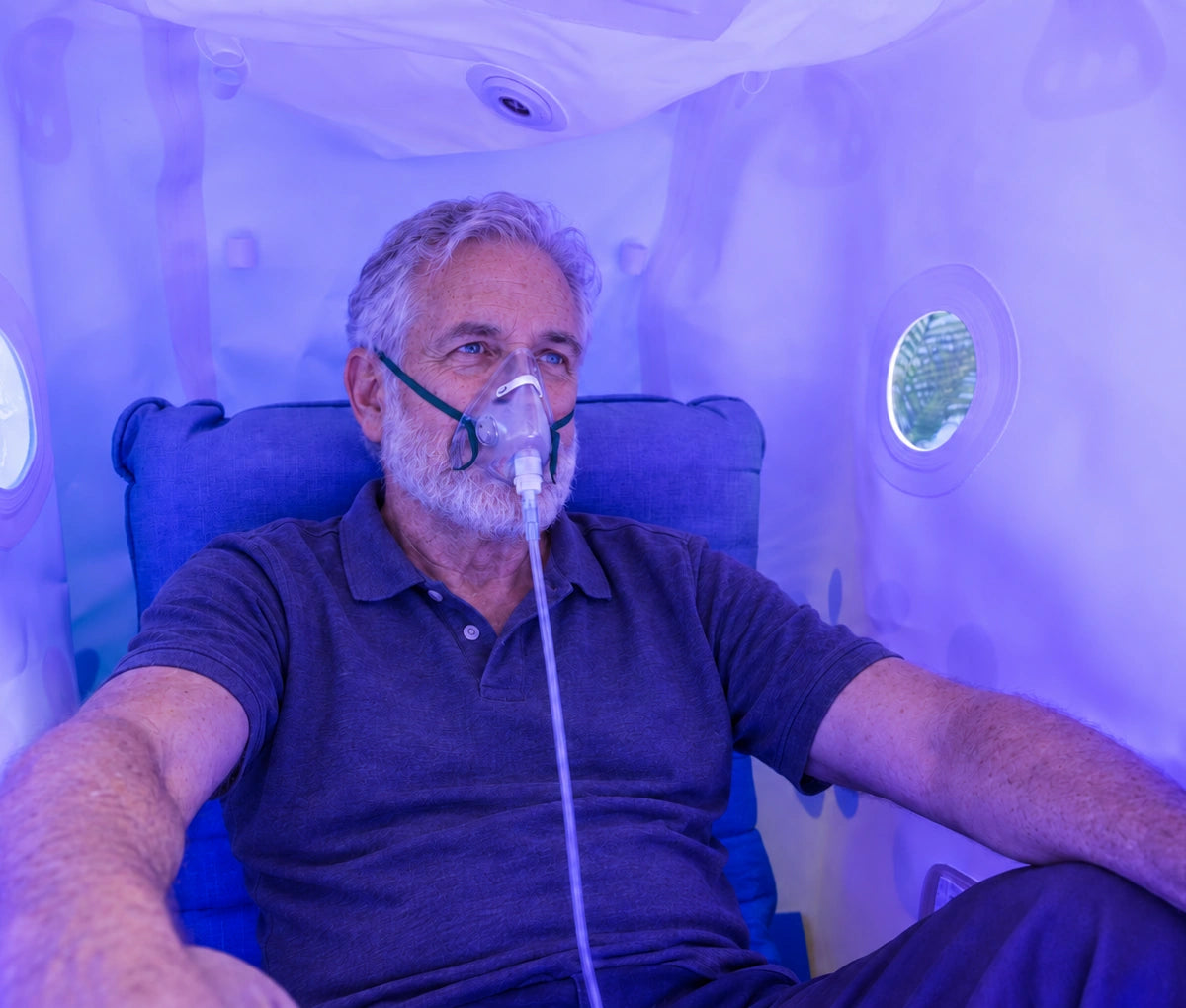 Man seated inside a Hyperbaric Oxygen chamber with an oxygen mask