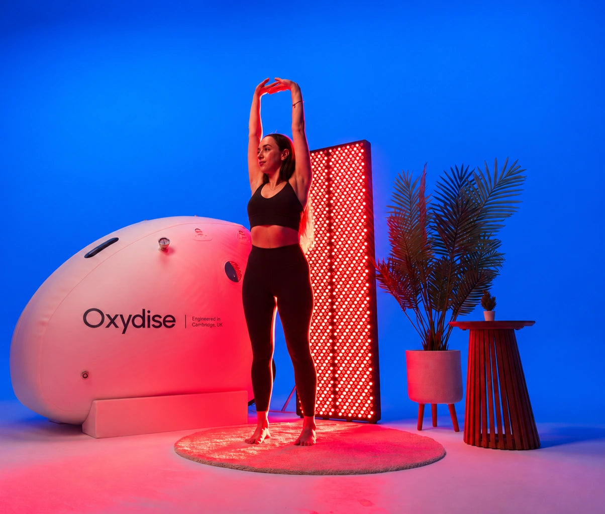 Woman stretching beside a Red Light panel and Oxydise Sitting Chamber with updated branding