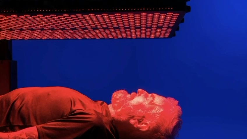 A person using an Oxydise Red Light Therapy panel